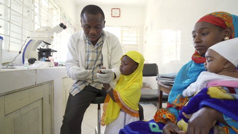 Doctor taking blood sample from female child patient. Africa