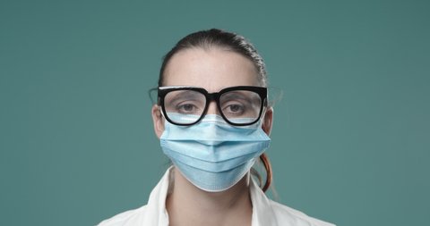 Woman wearing a protective surgical mask to prevent coronavirus, her glasses are fogged up