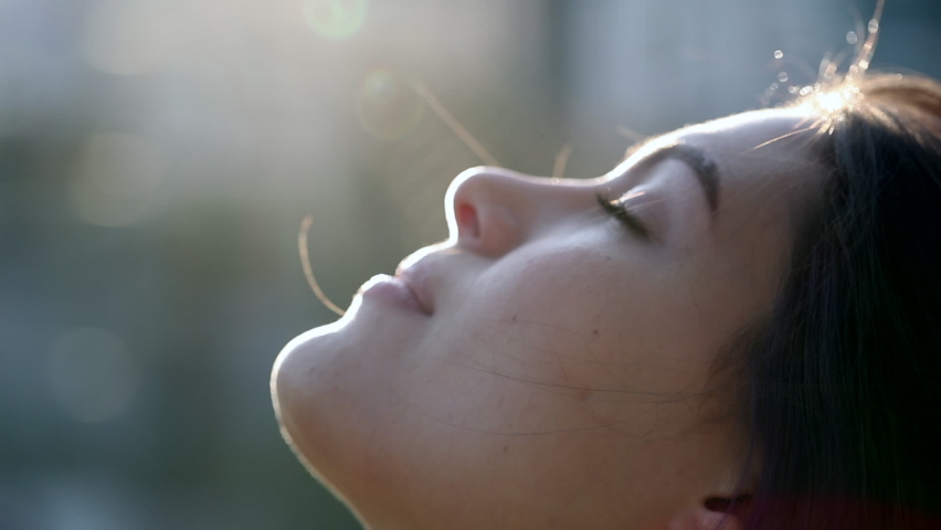 Contemplative young woman looking up to sky with faith and hope. Faithful girl profile face with lens-flare outside Royalty-Free Stock Footage #1060234013