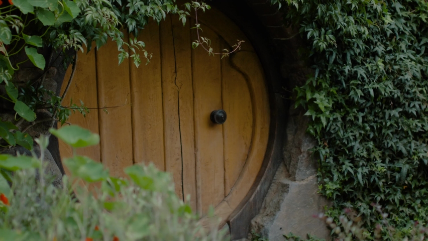 Round yellow hobbit door in a garden