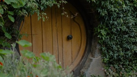 Round yellow hobbit door in a garden