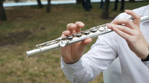 The musician plays in the garden at the celebration. Flute instrument Hands of a flute player playing the flute Classical orchestral instruments