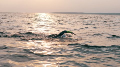 A man is swimming breaststroke through the sea.