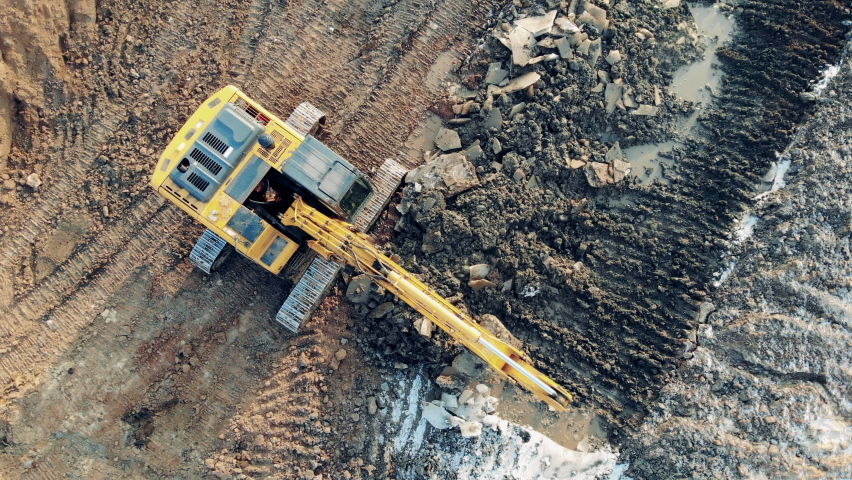 Working machine digs earth at a career. Construction equipment, heavy industry machinery. Yellow machine digs earth while working at a career. Royalty-Free Stock Footage #1060240151