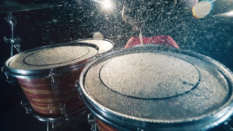Man plays wet drums in studio. Percussion instruments, close up.