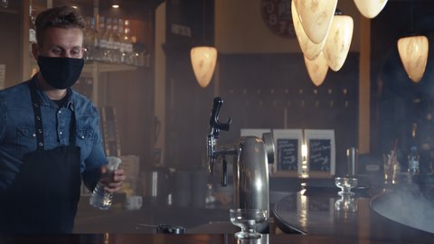 Barkeeper wearing face mask and an apron disinfecting the bar shot in 4k
