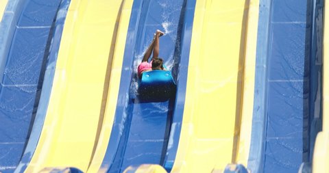 Water park summer fun. Kids having fun on the water slide with friends and familiy in the aqua fun park glides, happy into water splashes are all over. People playing on water slide in aqua park