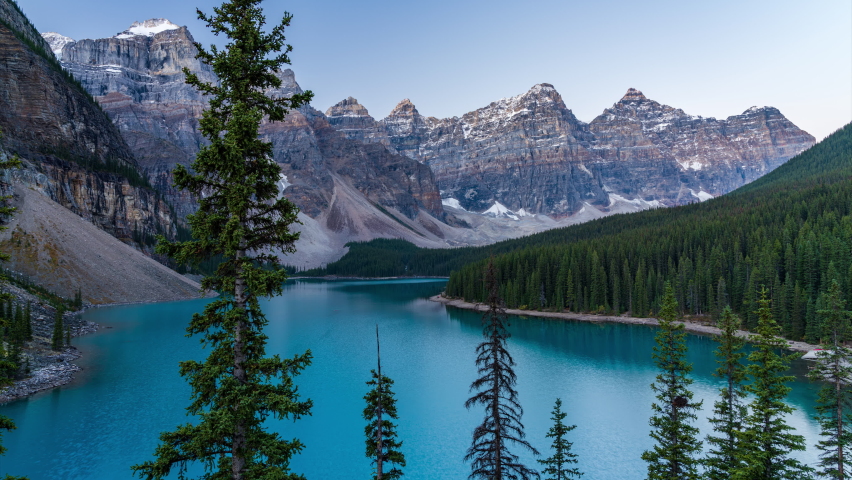 Moraine lake during sunrise time in summer sunny day. Red snow-covered Valley of the Ten Peaks reflection on turquoise color water surface. Banff National Park, Alberta, Canada. Time-lapse 4K Royalty-Free Stock Footage #1060250168
