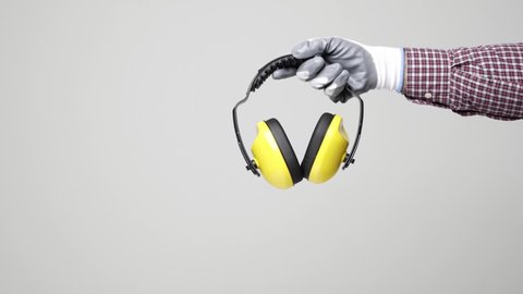 Close up hand of engineer holding earmuff on isolated white background. Engineer equipment concept. 4k resolution.