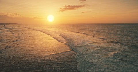 Slow motion of ocean waves at sun set light aerial view. Sunset wavy seascape at tropical paradise resort of Sumba Island, Indonesia, Asia. Cinematic nobody nature scenery at soft sunlight drone shot