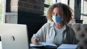 remote training, pretty girl student in medical mask is being trained online while sitting at table by window in restaurant