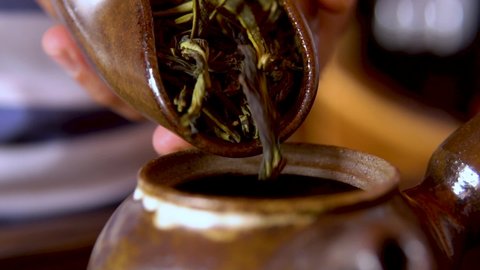 Oolong chinese tea, dried leaves in cha he close-up. Man pouring tea into a kettle.