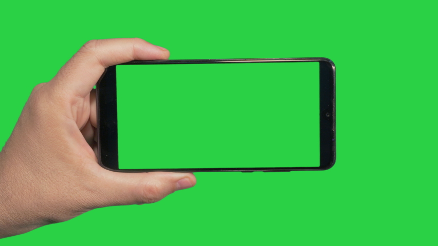 Hands holding cell phone with green screen in green background | Shutterstock HD Video #1060271630