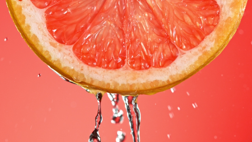 Super Slow Motion of Water Splash on Fresh Backlit Grapefruit Slice. Shot in 1000 fps. Royalty-Free Stock Footage #1060272779
