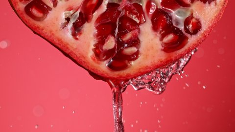 Super Slow Motion of Water Splash on Fresh Backlit Pomegranate Slice. Shot at 1000 fps.