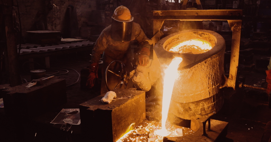 Close-up front view of a factory worker pouring molten metal into casts at a steel casting foundry Royalty-Free Stock Footage #1060273535
