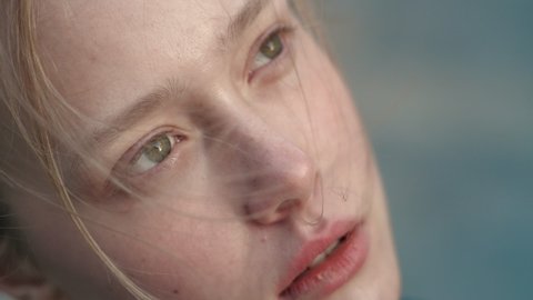 Close up of Woman’s Face, Girl opening her Beautiful green Eyes, Wind blowing on Blonde Hair. Natural Beauty Baby Face Female. Gorgeous woman looking thoughtfully to the Sky. Slow-motion.