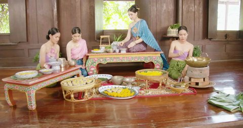 A beautiful asian female chef dress on Ayutthaya cultural fashion clothes sitting and sweet cooking training traditional Thailand tomyam food in the vintage old style ancient house