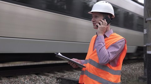 Railway engineer talking on the phone near the railway.