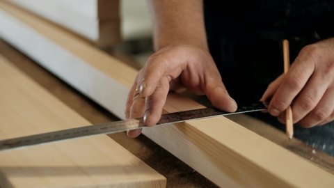 Carpenter working in the carpentry workshop. Worker takes measurements. Carpentry, craftsmanship, handwork concept.