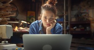 Portrait of young pensive ginger female happy using laptop staying online indoors artisan, pleasant Hispanic woman working with computer smiling staying up to date connected to internet in workshop