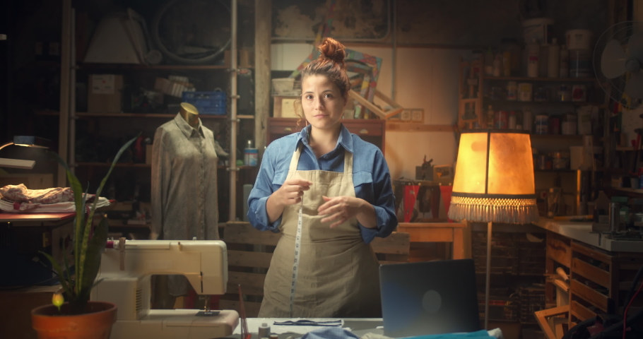 Vintage style beautiful tailor female looking to camera pensive standing in atelier studio, attractive young woman entrepreneur in apron at cozy workplace workshop, fashion style and clothes concept Royalty-Free Stock Footage #1060285139
