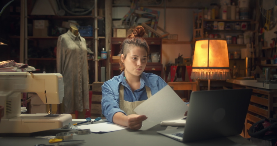 Beautiful female sadly throwing away paper unsuccessful project stressful moment indoors, depressive sad young woman artisan fashion designer in apron working sitting next to work-desk in workshop Royalty-Free Stock Footage #1060285160