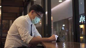 Confidence Asian business man office worker using digital tablet with internet for online working or text message at coffee shop. Businessman wearing face mask during protect covid-19 virus pandemic