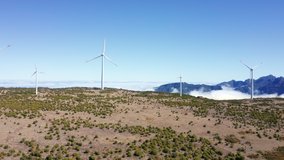 4K Drone footage of wind generators in field with mountains in background. Alternative energy source concept.