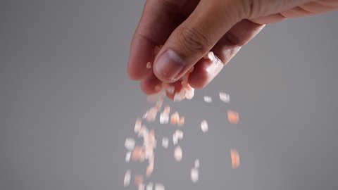 Pink salt falling from hand in slow motion