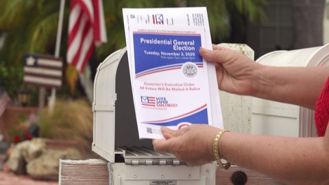 Older American woman receives absentee election ballot in the mail. Close up of mailbox and hands. Illustrative editorial taken in Vista, CA / USA - October 8, 2020: