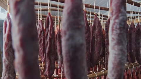 Racks of smoked spicy sausages hanging in the smokehouse. Meat production. Sausage and salami sticks variety. Close-up.