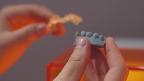 Printing dental models in stomatology. Close-up of male worker dentist applying dental bridges on prosthetic 3D printed denture model. Digital dentistry.