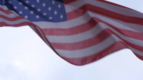 American flag waving in the wind in slow motion with a grey sky as background. Patriotic and nationalistic themed concept.