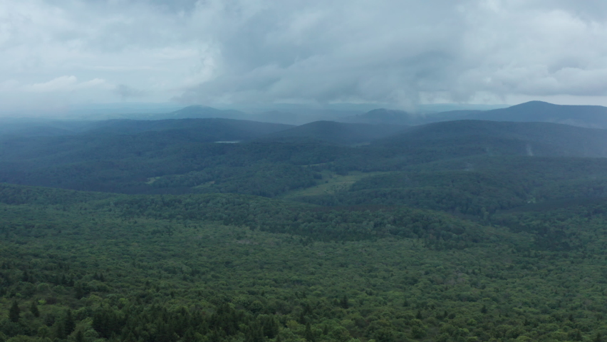 An aerial shot (dolly out) of the Seneca Creek Valley and the lookout tower on top of Spruce Knob, the highest point in West Virginia. The sky is full of clouds.