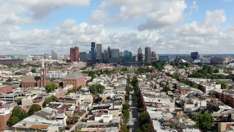 Aerial truck shot, Baltimore Maryland USA skyline, cityscape on summer day, downtown financial business district, neighborhood homes and community housing in foreground