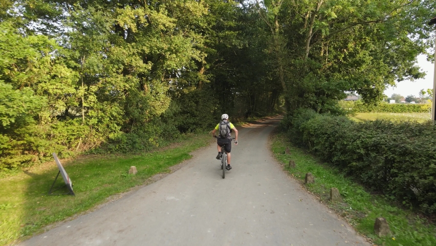 Mountain biker riding along narrow Lane drone fast tracking through trees summers day in Essex UK | Shutterstock HD Video #1060295279