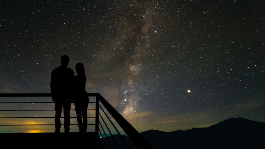 The couple standing on the balcony on the starry sky background. hyperlapse.