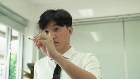 A young Asian businessman writes the word goals on the board, the concept of achieving goals.
