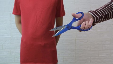 A person clicking the scissors in front of a boy, traditional circumcision procedure concept.