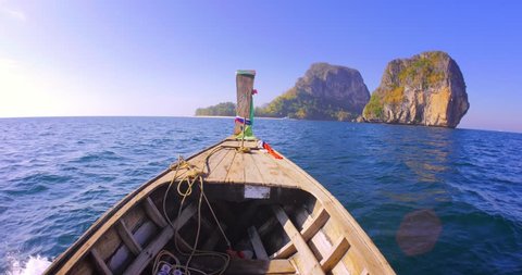 Adventure background. Marine landscape with wooden fishing boat going to distant rocky island at early sunset near Phuket in Thailand
