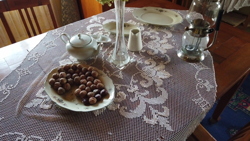 Plate with nuts, old kettle and a vase with flowers. Composition on the table in an old house beginning of the 20th century. Old Celtic village.