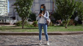 Asian woman in a disposable protective medical mask looking at smartphone 4K