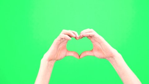 Closeup view of male hand making heart shape gesture isolated on green screen chromakey background. Person forms a heart shape using their fingers. Two handed gestures. Chromakey. Green Screen