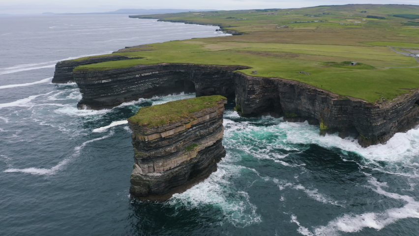 Aerial view of an astonishing sea stack, Dun Briste in Mayo. Legend attests that St Patrick drove all the vipers from Ireland onto the stack on Downpatrick Head, leaving the mainland snake-free. Royalty-Free Stock Footage #1060315703