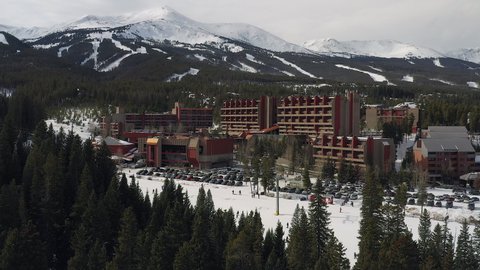 Rising drone footage of the Beaver Run Resort and Conference Center, Breckenridge mountain range (Peak 8), and a ski lift with skiers and snowboarders in Breckenridge, Summit County, Colorado.