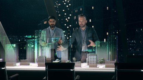 In the Near Future: Professional Designer in Suit Working on Architecture Project with Partner standing around Futuristic Table Using Holographic Modern Augmented Reality Technology.