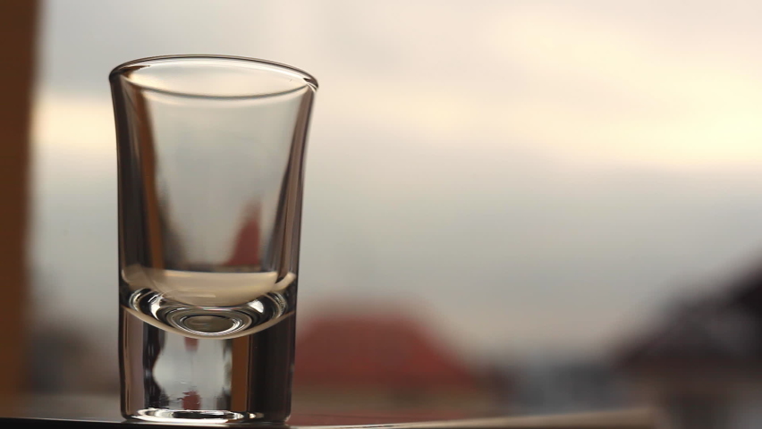 Shot of high alcohol volume yellow spirit drink being poured from bottle close-up footage. Beverage concept.
