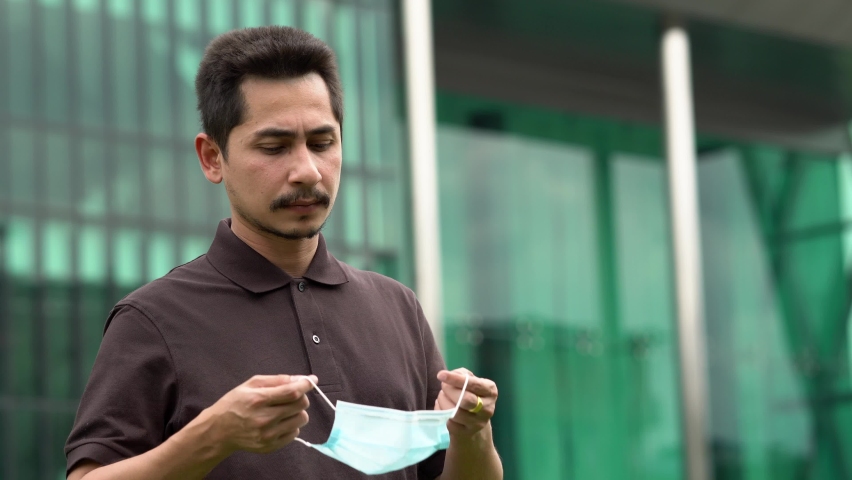 Handsome young man standing outdoors wearing medical mask to protect others from virus spread