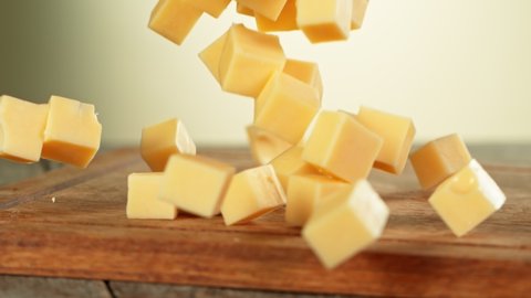 Super Slow Motion Shot of Cheese Chunks Falling on Wooden Board at 1000 fps.